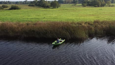 circulating drone shot with man on fishing boat who are fishing in the river near reeds