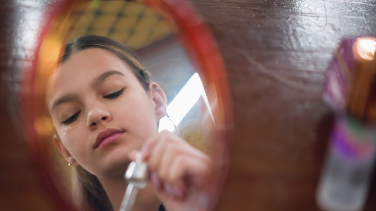 Mirror reflection of young lady carefully applying makeup on face, focused expression highlights beauty routine, skincare, and closeup shot emphasizes precisionand personal grooming