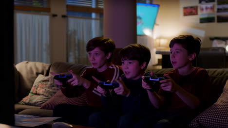 three boys playing video games on a couch