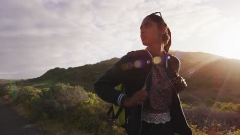 Mixed-race-woman-walking-on-road-hitchhiking-on-sunny-day