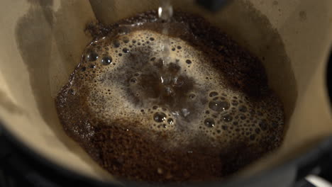 dripping hot water over ground coffee in filter