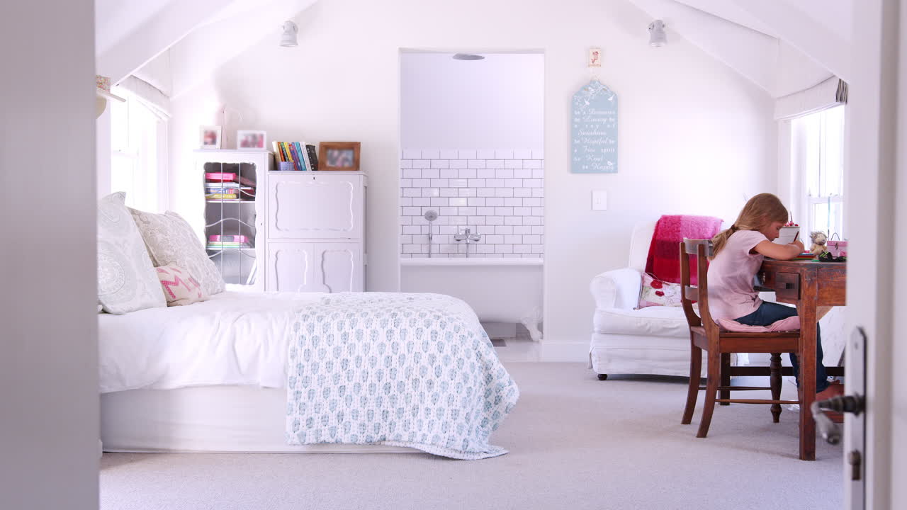 책상에 앉아서 방에서 숙제를 하고 있는 젊은 백인 소녀