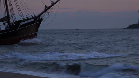 lighthouse and sailing ship at sunset