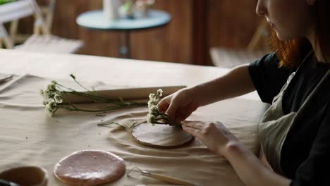 A-red-haired-potter-makes-flower-prints-on-earthenware