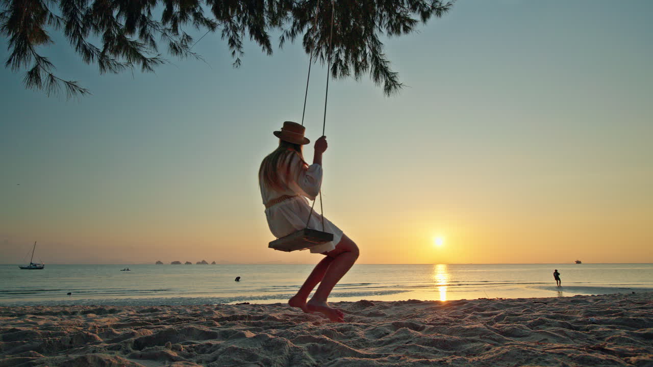 Donna su un'altalena al tramonto sulla spiaggia