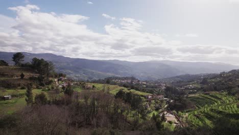 paisaje de granjas en una zona rural de portugal, con pequeñas montañas en el fondo y un cielo nublado