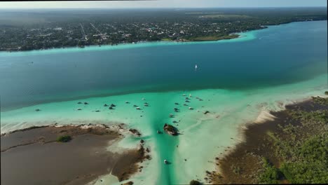 aerial view overlooking boats at the pirates channel revealing the bacalar town in the background, in mexico