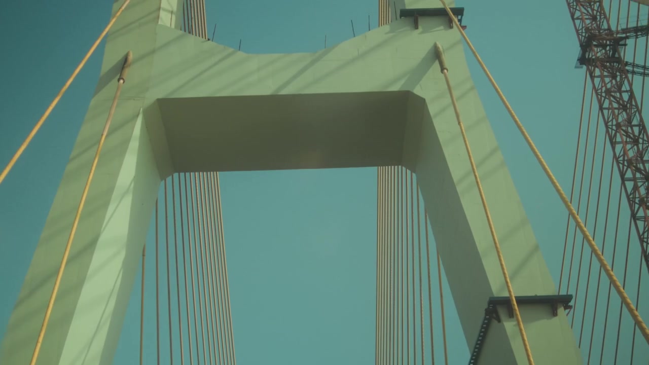 Upward view of a modern cable-stayed bridge filmed from a moving vehicle. Dynamic transportation infrastructure scene featuring geometric lines, engineering, and urban travel.