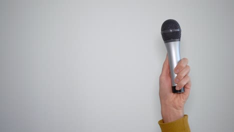 man's hand holding a microphone vertically concept of singer and music