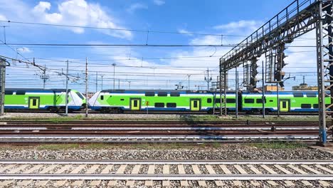 a green train moves through milan railway