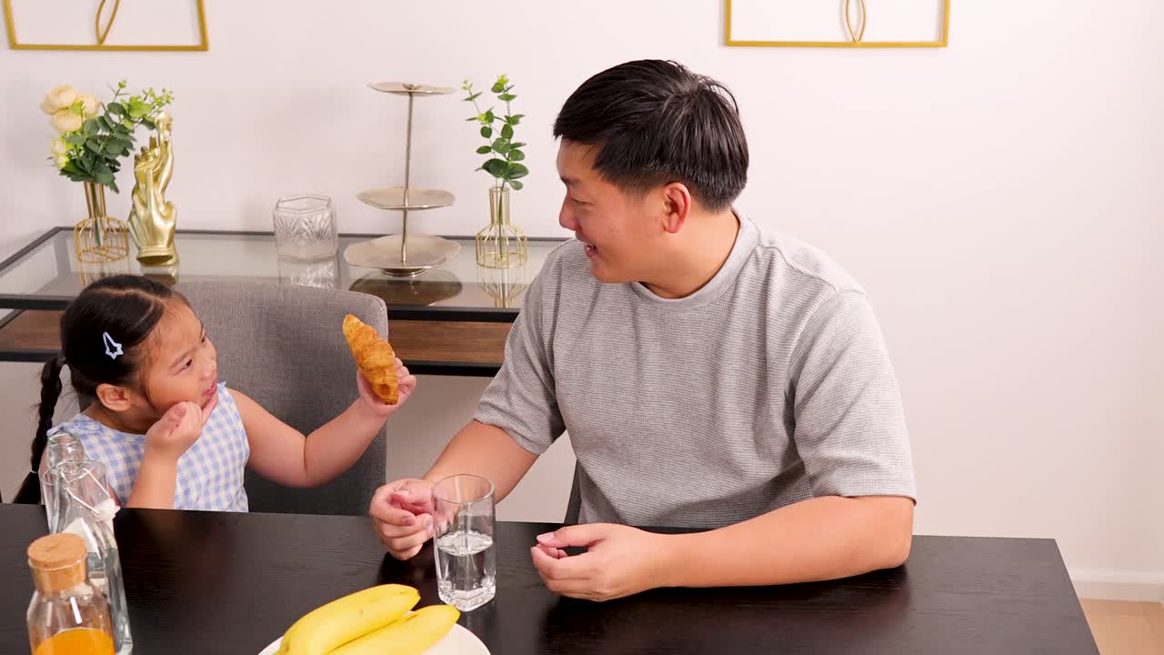 A father and daughter share a joyful breakfast in a bright, cozy dining room, fostering family bonding and happiness