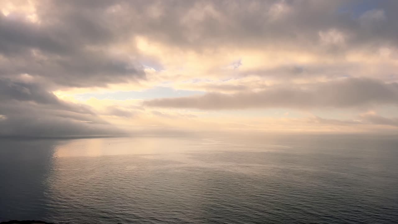 lapso de tiempo de nubes en movimiento sobre la superficie del agua de mar, luz solar de ángulo bajo en el horizonte, atmósfera tranquila y serena de apariencia natural