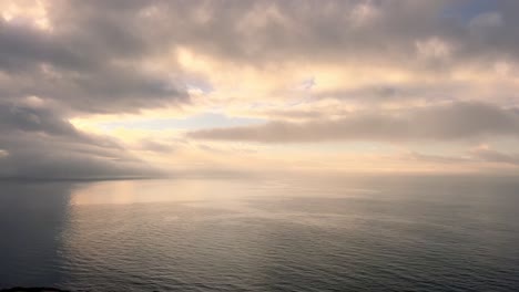 time-lapse of moving clouds over wast sea water surface, low angle sunlight at horizon, tranquil and serene atmosphere of natural appearance