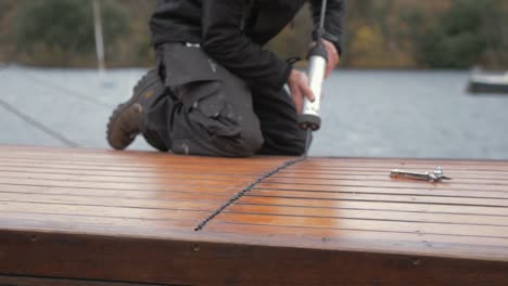 carpenter sealing roof planking of boat cabin with sealant gun