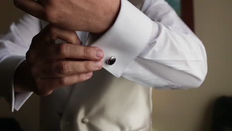 close up of male hands putting a cufflink getting ready for event