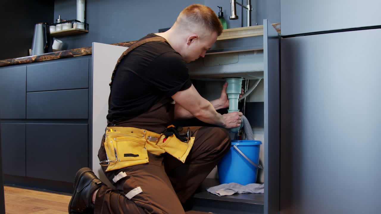 Plumber repairing a sink in the kitchen