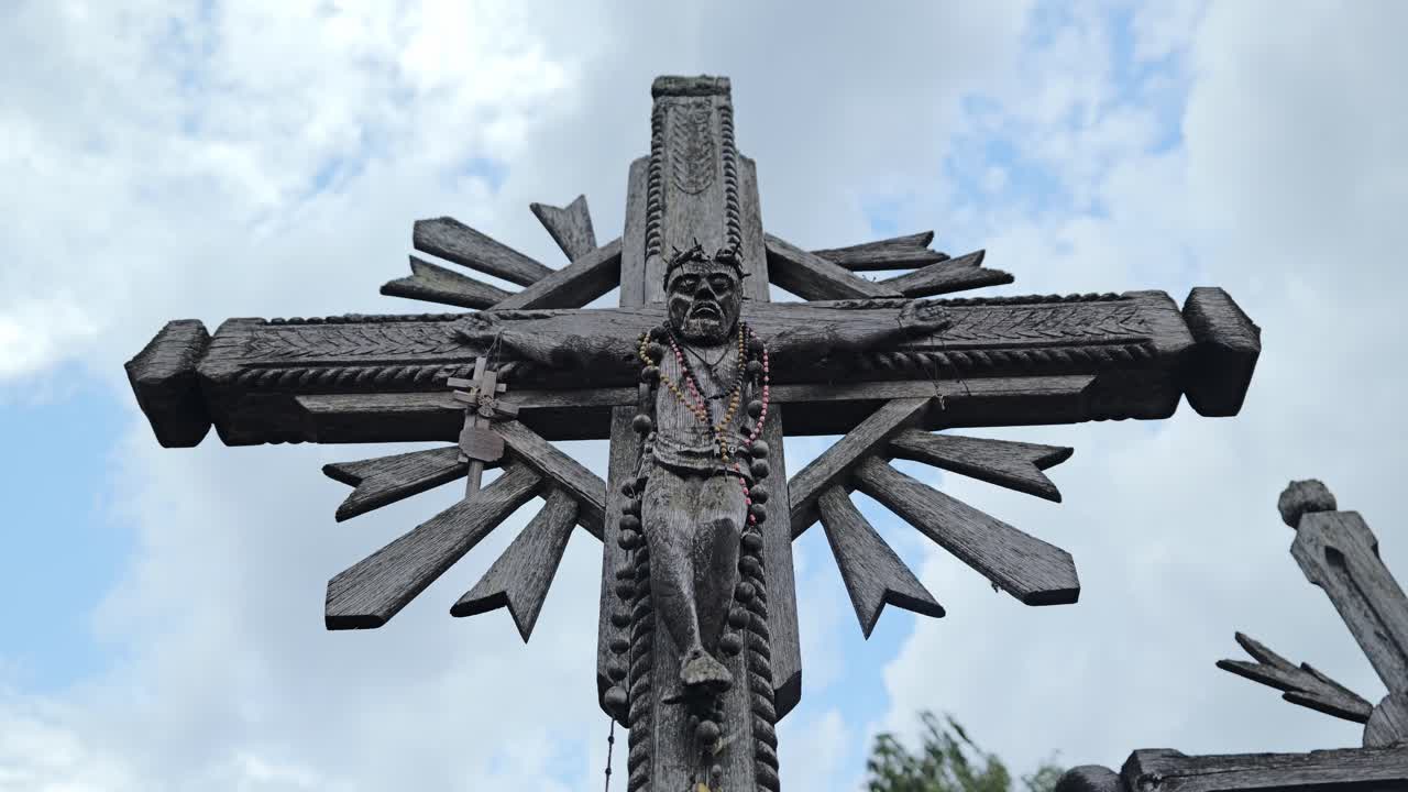 Trækrucifiks-skulptur, der står udendørs på et pilgrimssted i Litauen om dagen