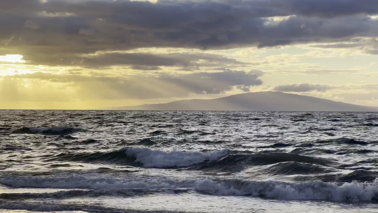 Cinematic panning shot of the private island of Lanai at sunset from Wailea Beach in South Maui, Hawai'i