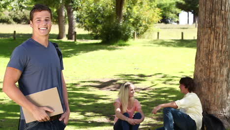 Man-waving-towards-his-friends-who-are-sitting-behind-him-before-he-looks-at-the-camera