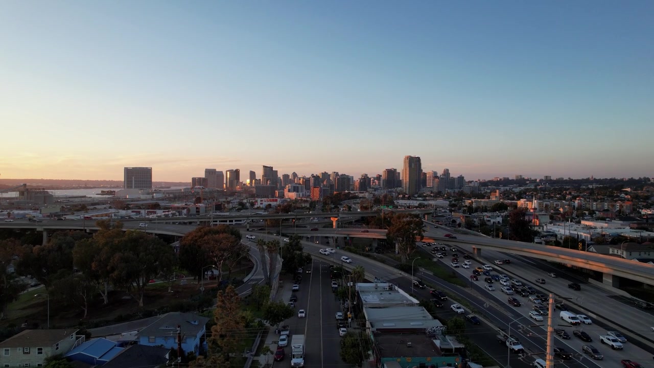 Drone in ascesa al tramonto che rivela un'ampia vista dello skyline del centro di San Diego con una calda luce dorata e un cielo colorato