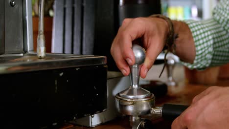 camarero presionando café molido en un portafiltro
