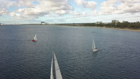 sailboats form single line as they navigate through