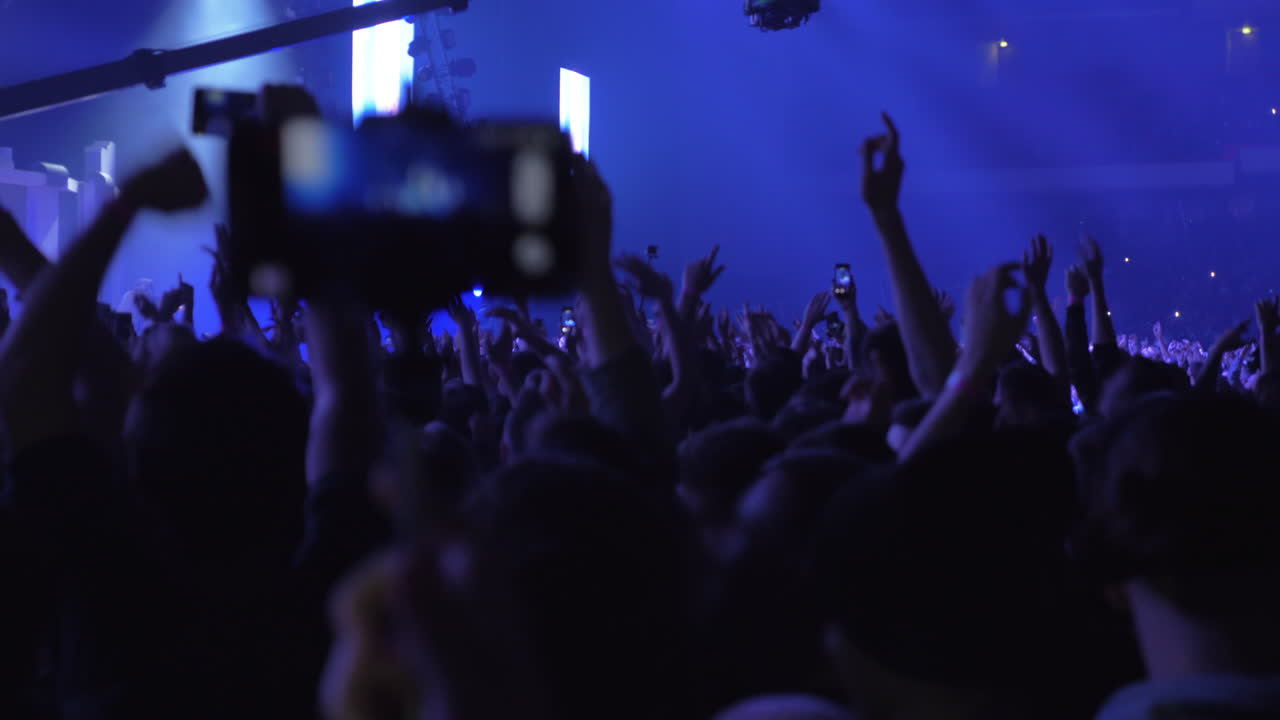 Pessoas dançando e levantando as mãos no show.