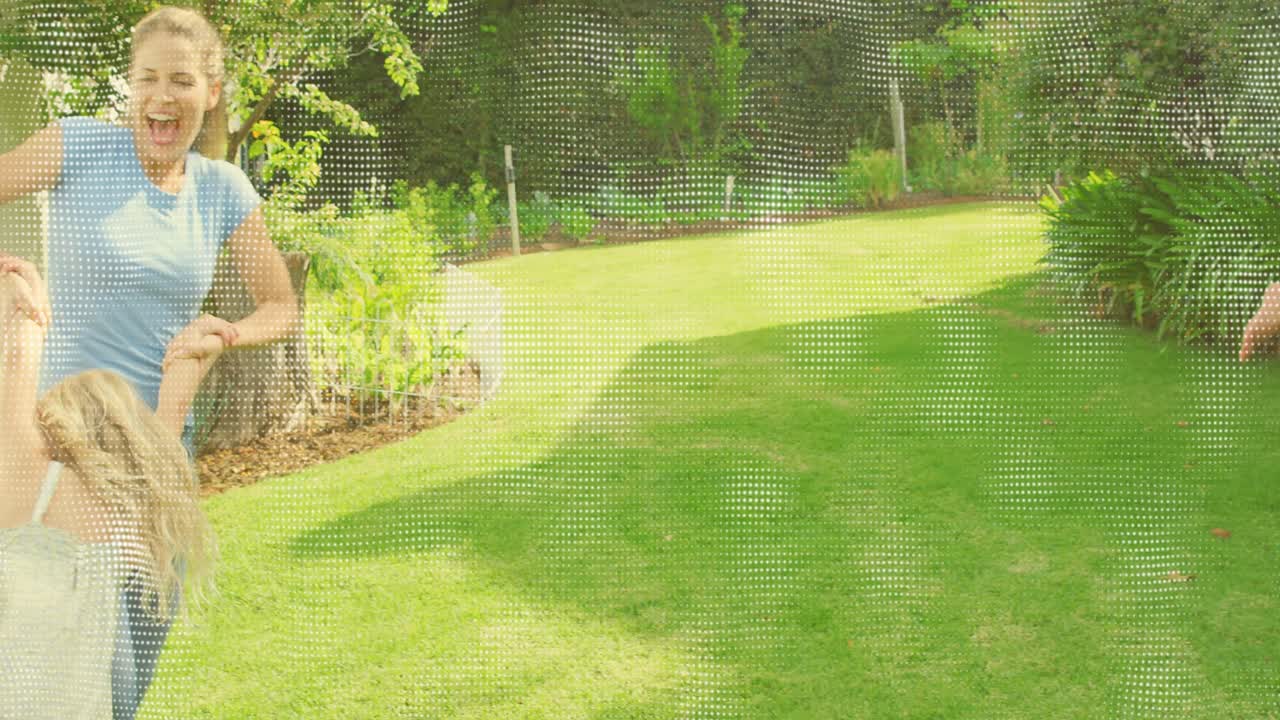 Man lifting girl by arms, swinging over lawn, releasing left, woman spinning child, family playing