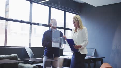 Diverse-business-colleagues-standing-talking-going-through-paperwork-in-modern-office