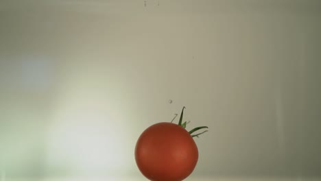 a tomato is dropping into the water with a bit more bubbles