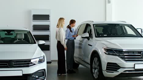 mujeres discutiendo detalles de automóviles en un concesionario