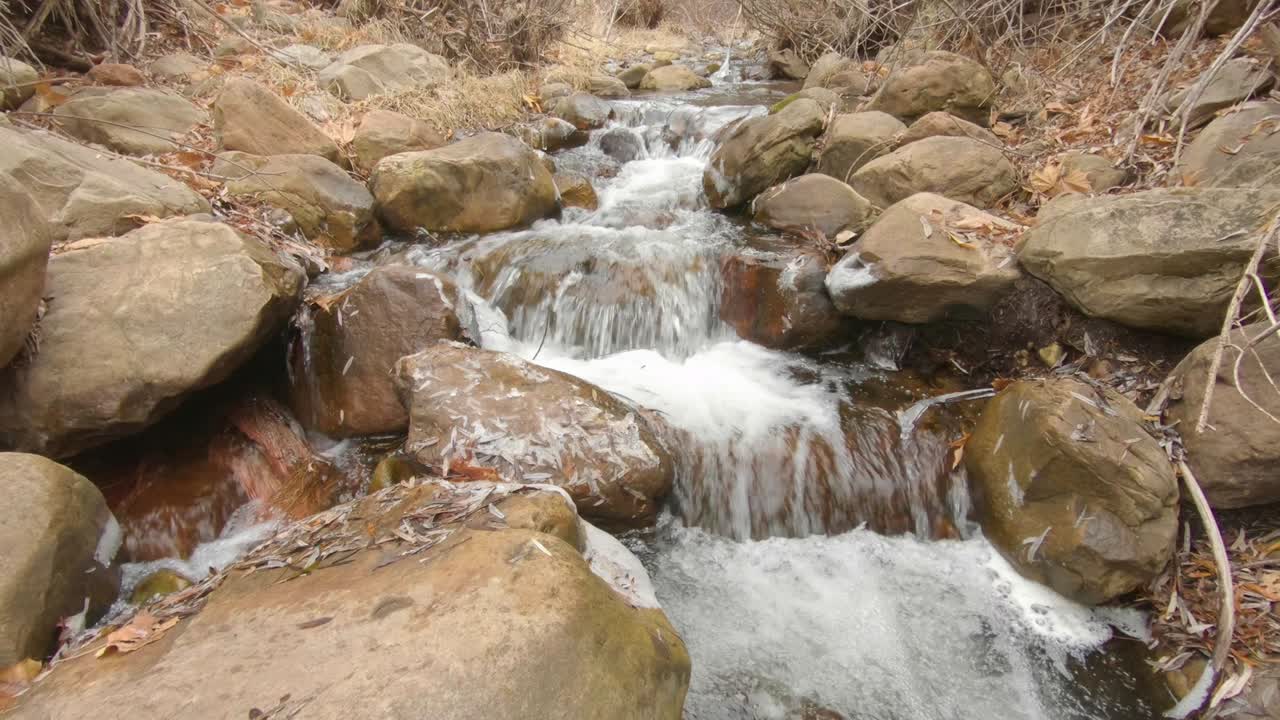 Establishing shot of a creek in Payson Arizona with water cascading over rocks in the fall