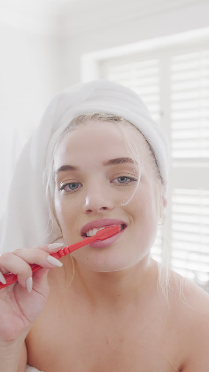 Vertical video of portrait of happy caucasian plus size woman brushing teeth in slow motion