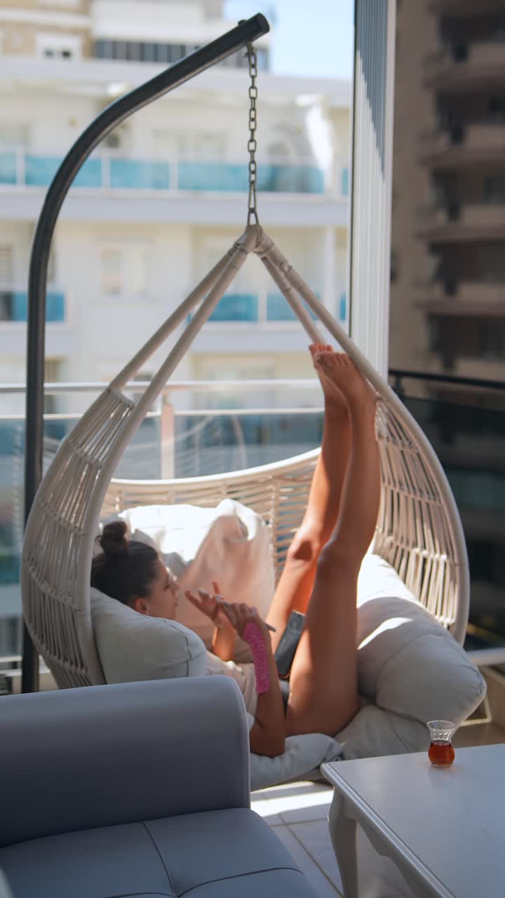 mujer relajándose en una silla colgante en un balcón