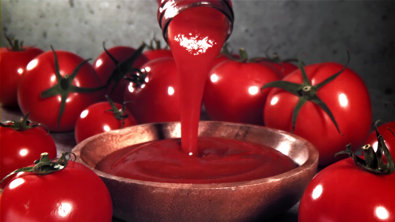 Ketchup versato in una ciotola con pomodori freschi
