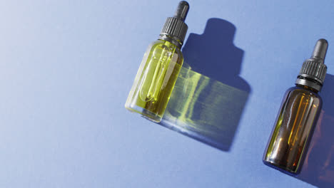 Close-up-of-dropper-serum-bottles-on-blue-background-with-copy-space