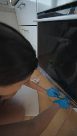woman cleaning kitchen oven