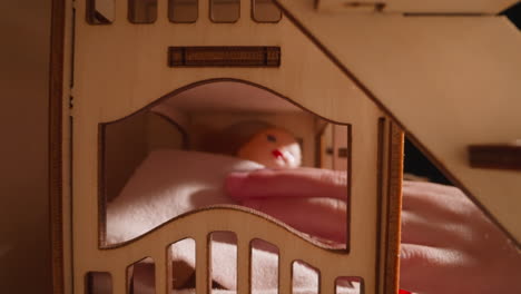 little kid calms down covered dolly on bed in toy house