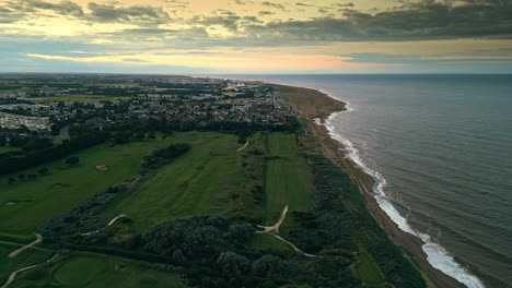 Explore-Skegness-through-aerial-drone-video-at-sunset,-featuring-holiday-park,-caravans,-sea,-and-wide-beach