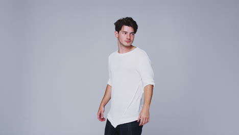 studio shot of man walking into frame against white background and dancing in slow motion