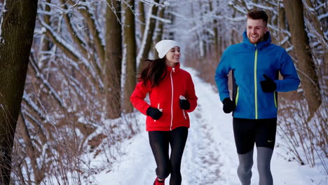couple running in a snowy winter forest