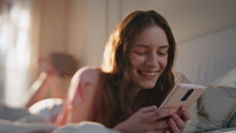 relaxed girl holding smartphone lying on bed closeup. carefree female laughing