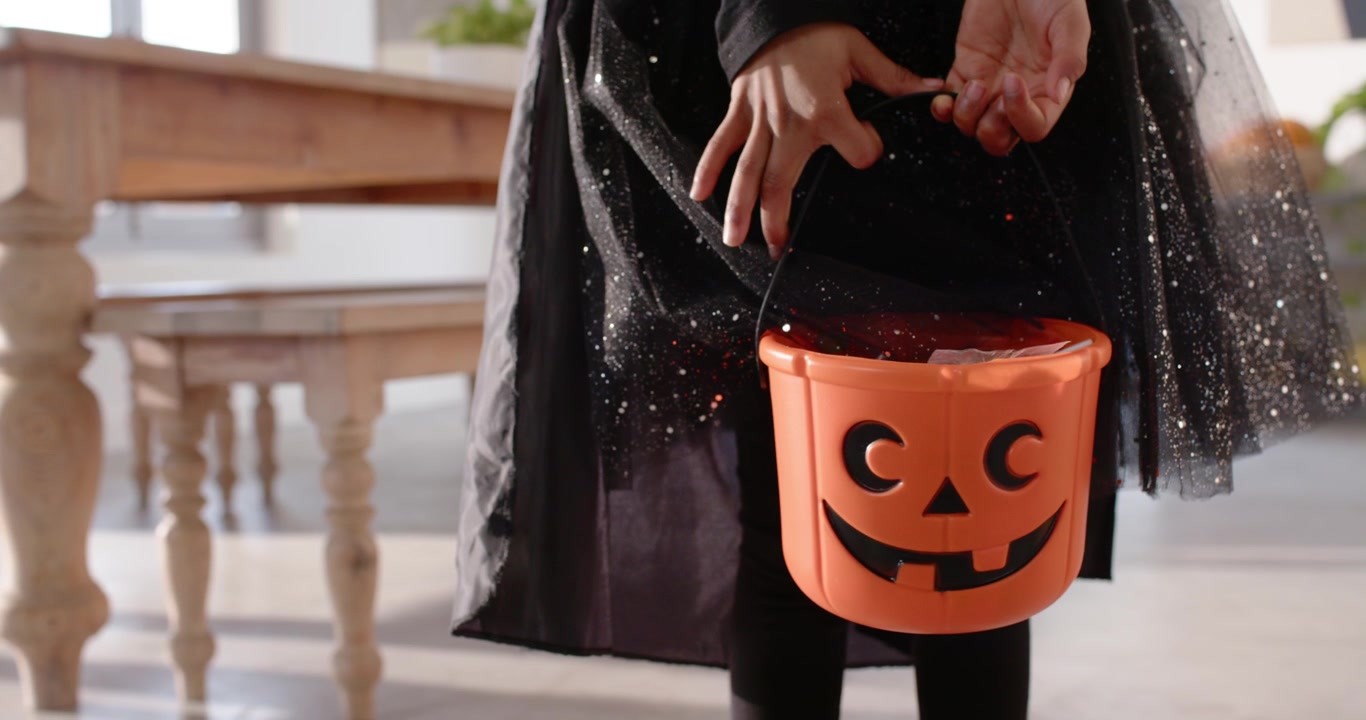 Il bambino sente gli oggetti spostarsi, regola il manico del secchiello a forma di zucca arancione e controlla i dolcetti vicino al tavolo