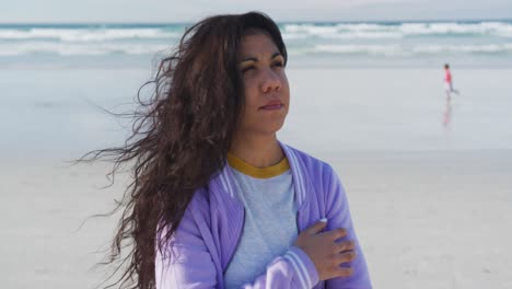 Mixed-race-woman-looking-away-at-the-beach-on-sunny-day