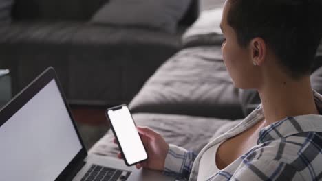 Woman-using-smartphone-and-laptop-in-living-room