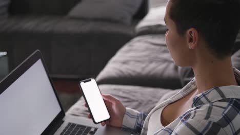 mujer usando teléfono inteligente y computadora portátil en la sala de estar