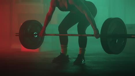 athletic woman is lifting barbell with weights in gym training her endurance and strength