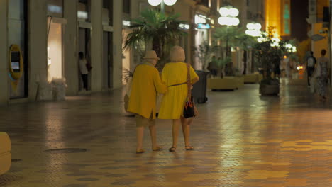 amigas ancianas caminando por la ciudad nocturna.