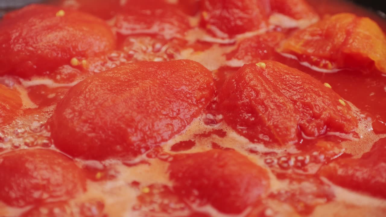 Cooking fresh peeled canned tomato Juice sauce in pan, peeled tomatoes boiling in their own juice, making tomatoes pasta sauce .Top view close up, Italian traditional cuisine food.
