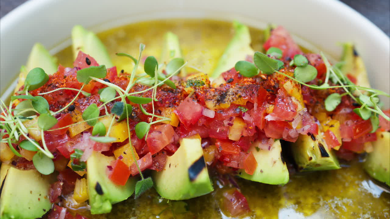 Close up of a woman eating avocado with cut up tomatoes